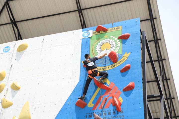 Atlet panjat tebing sedang beraksi memanjat dinding di Tangerang City Sport Climbing Center dengan latar belakang logo Piala Wali Kota.